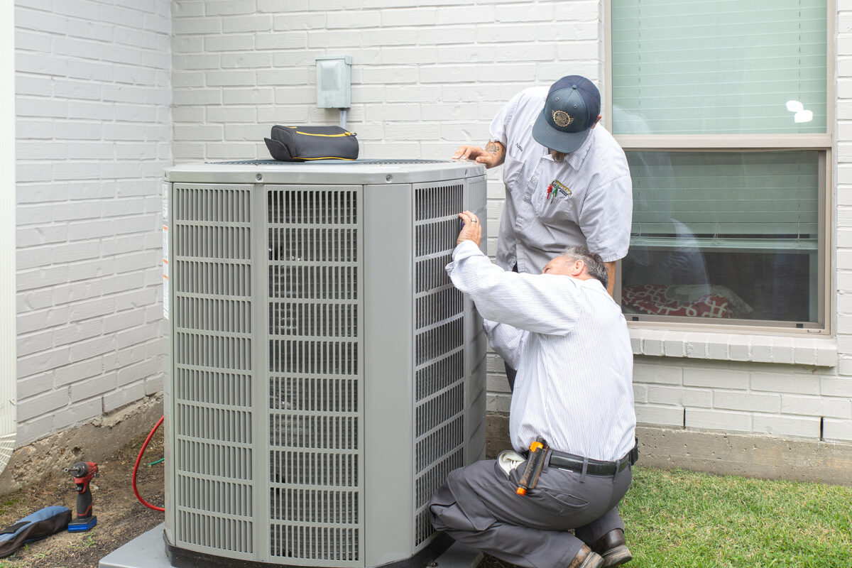 HVAC technicians working on an outdoor AC unit