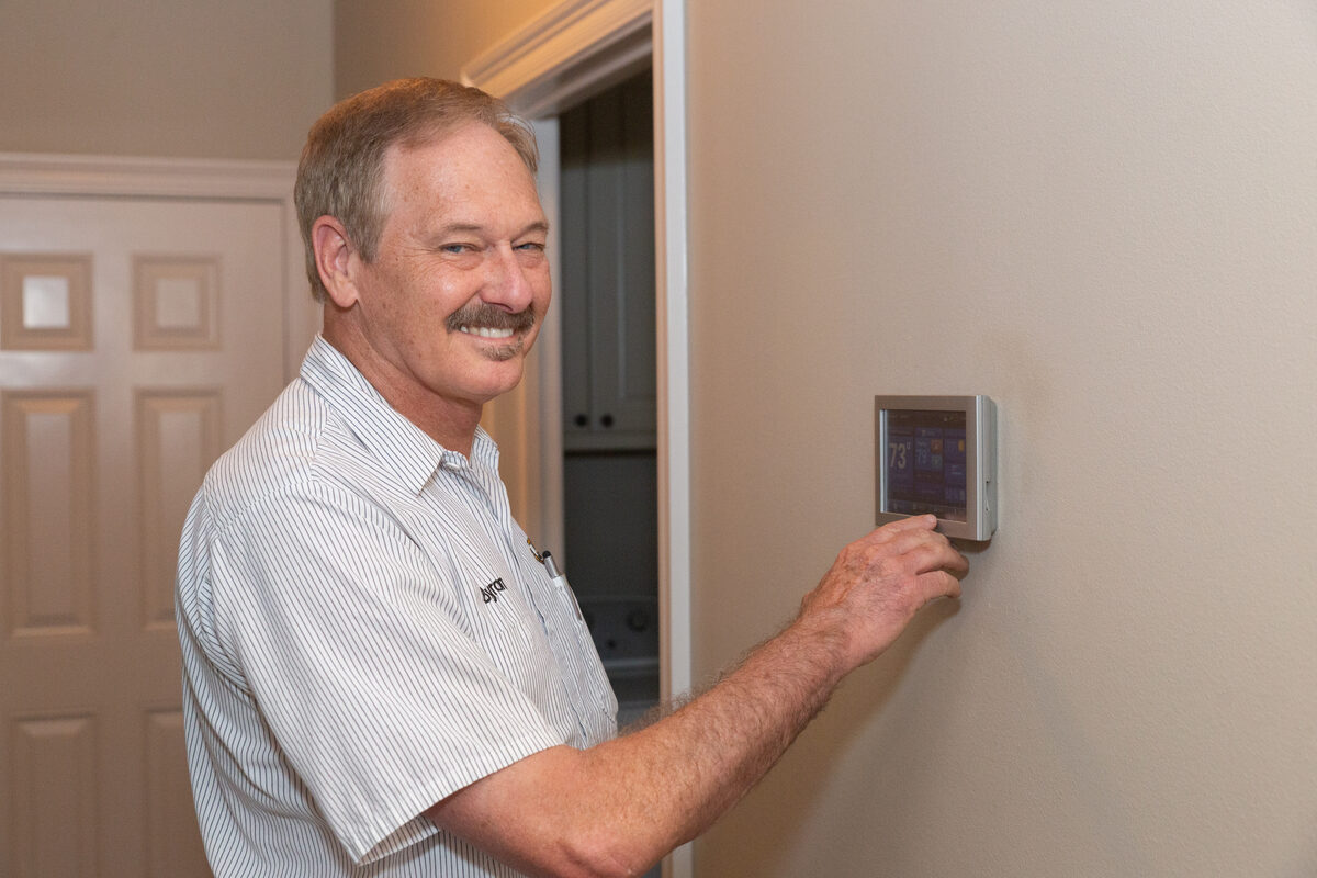 Person adjusting a wall thermostat
